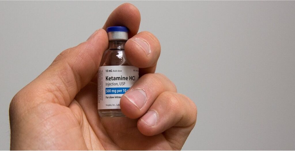 A vial of ketamine held in a gloved hand